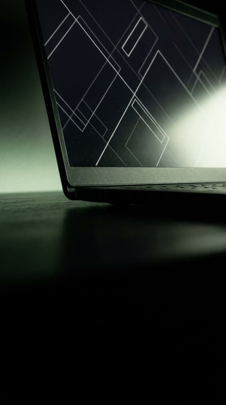 Laptop screen showing an abstract web application interface in a dark room
